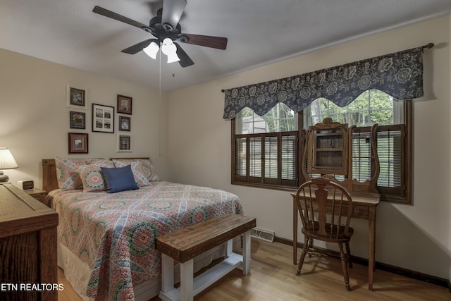 bedroom featuring baseboards, wood finished floors, and visible vents