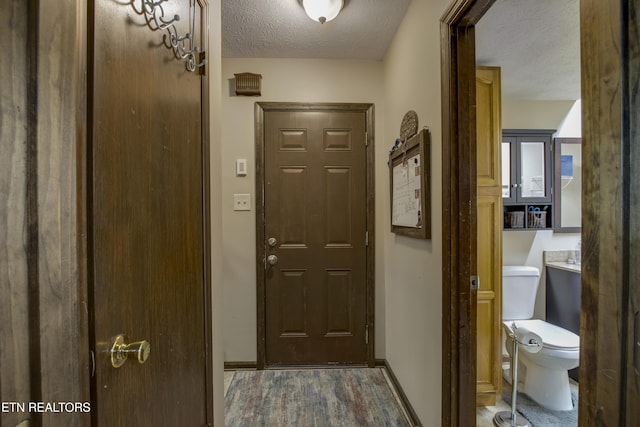 entryway featuring baseboards, a textured ceiling, and wood finished floors