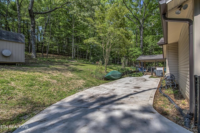 view of yard featuring an outdoor structure, driveway, cooling unit, a patio, and a storage shed