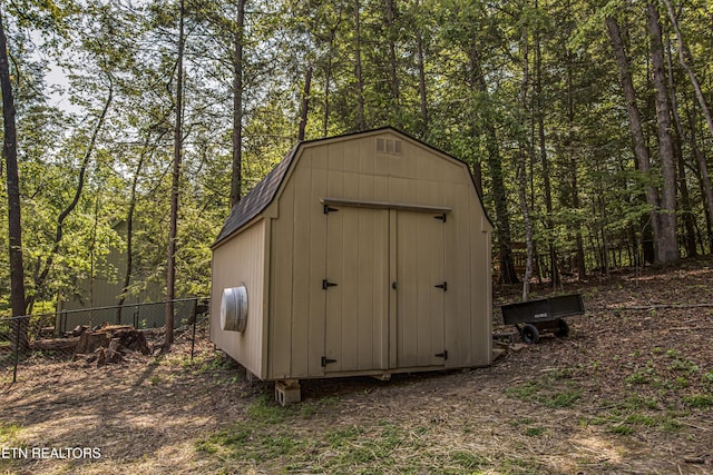 view of shed featuring a view of trees and fence