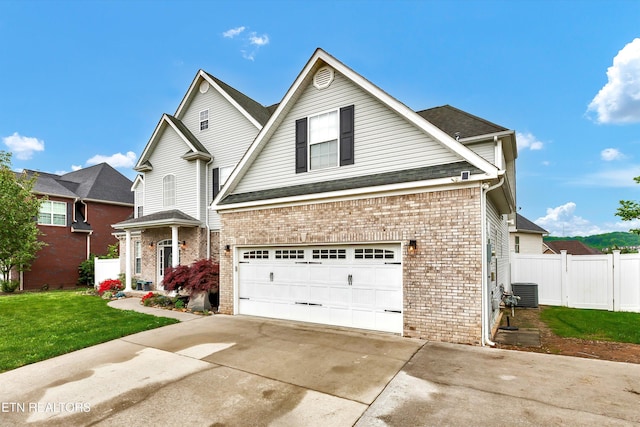 traditional-style house featuring a front lawn, a garage, brick siding, concrete driveway, and fence
