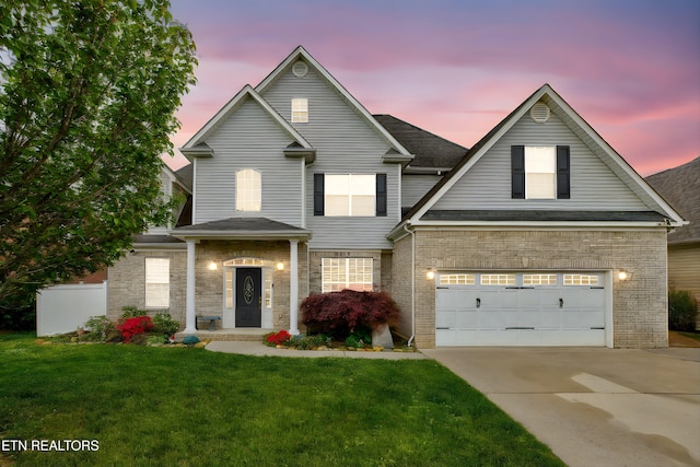 traditional-style home with driveway, a shingled roof, a front lawn, brick siding, and a garage