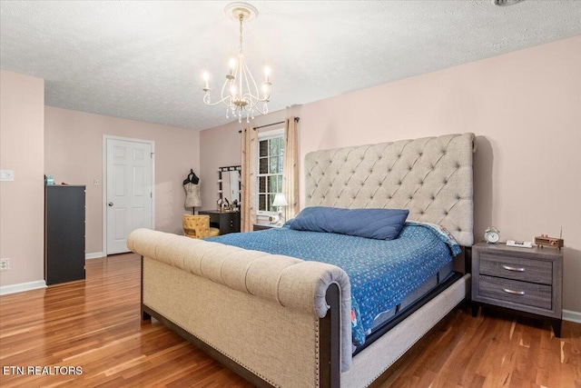 bedroom featuring baseboards, wood finished floors, and a notable chandelier