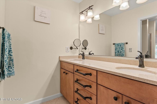 bathroom with double vanity, baseboards, tile patterned flooring, and a sink