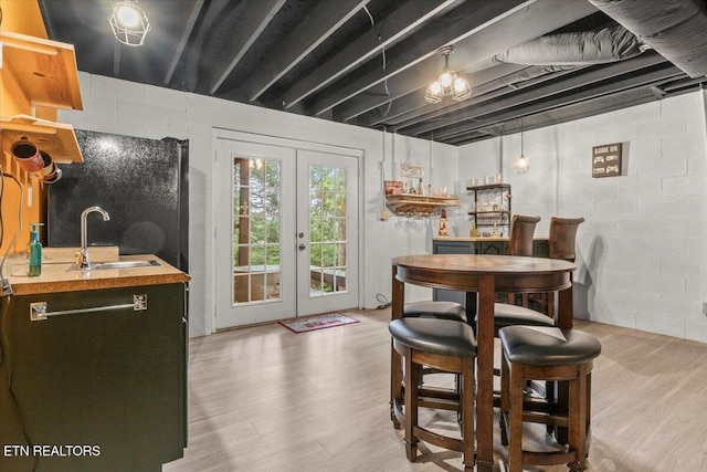 dining space with wood finished floors, french doors, bar, and concrete block wall