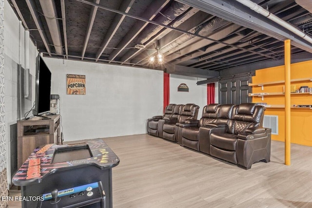 home theater room featuring concrete block wall, visible vents, and wood finished floors