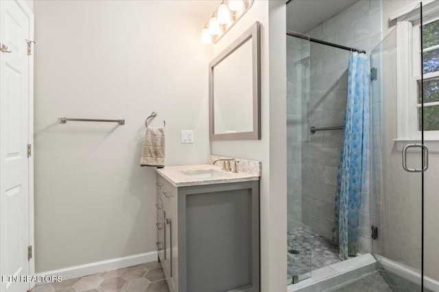 bathroom with baseboards, a stall shower, and vanity