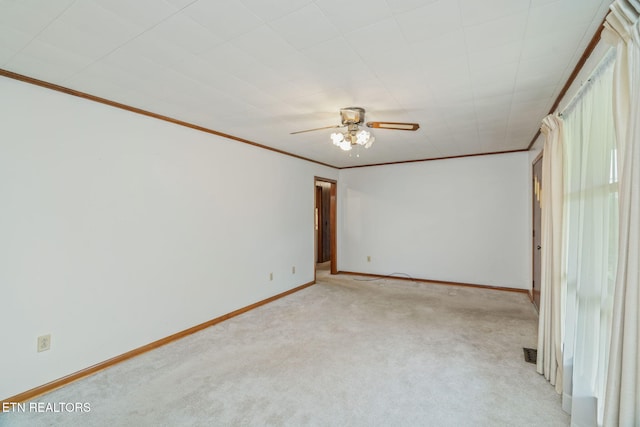 empty room with crown molding, light colored carpet, visible vents, baseboards, and a ceiling fan