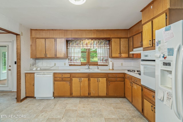 kitchen featuring white appliances, light countertops, under cabinet range hood, and a sink