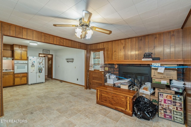 office with baseboards, wood walls, ceiling fan, and a glass covered fireplace