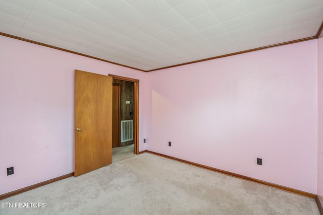 carpeted empty room with ornamental molding, visible vents, and baseboards