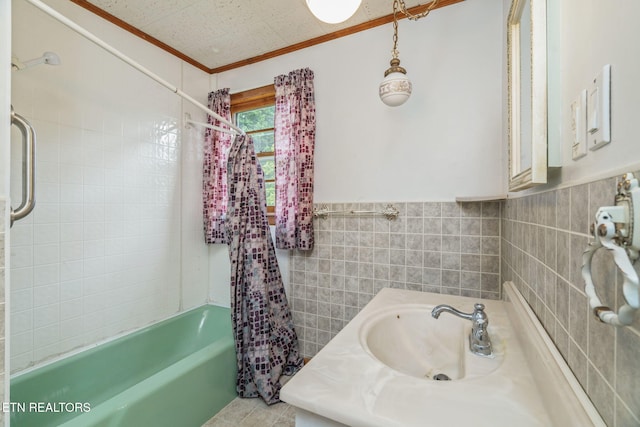 full bathroom featuring tile walls, a sink, ornamental molding, wainscoting, and  shower combination