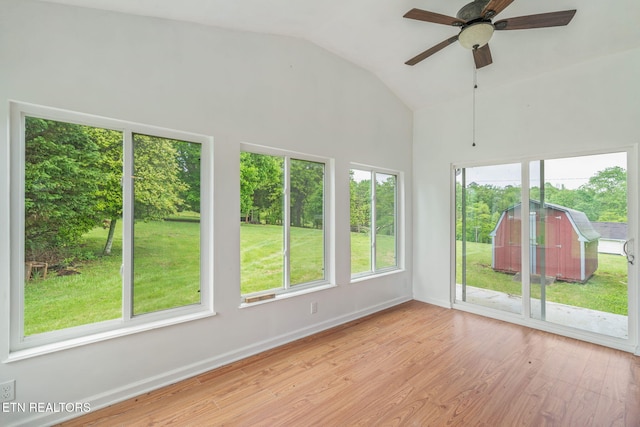 unfurnished sunroom featuring baseboards, wood finished floors, and lofted ceiling