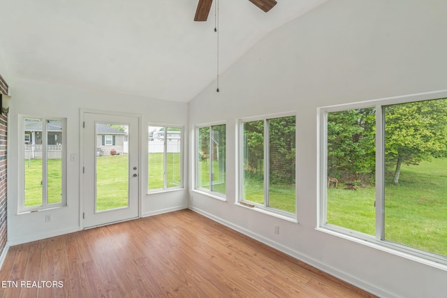 unfurnished sunroom featuring high vaulted ceiling, wood finished floors, and baseboards