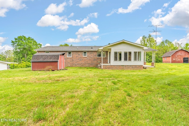 back of house with brick siding, a shed, an outbuilding, and a lawn