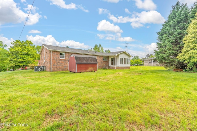 rear view of property featuring an outdoor structure, a lawn, a storage unit, and brick siding