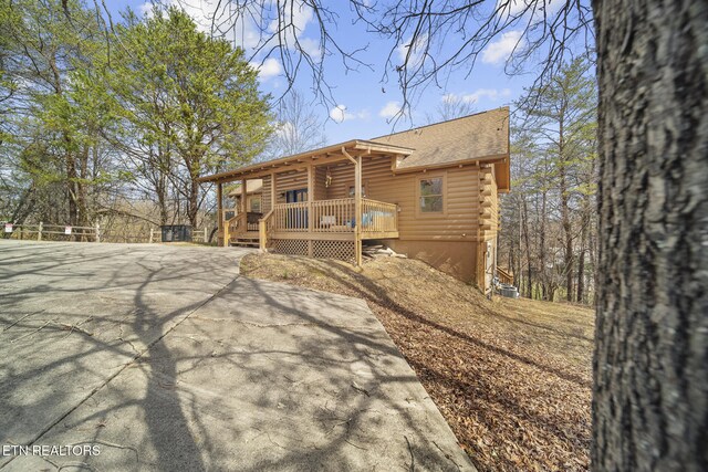 back of property featuring a shingled roof, a wooden deck, and log exterior