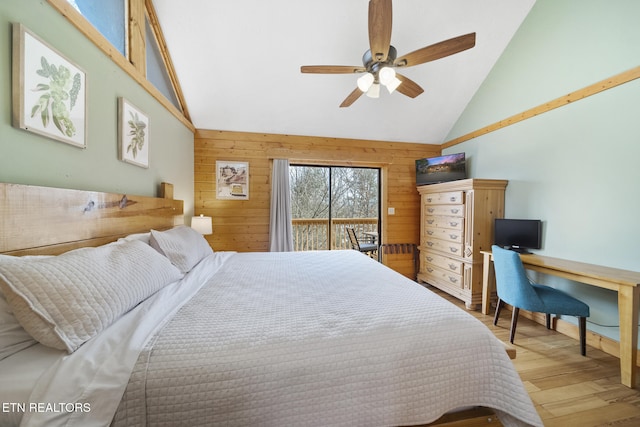 bedroom with access to outside, wood walls, wood finished floors, and high vaulted ceiling