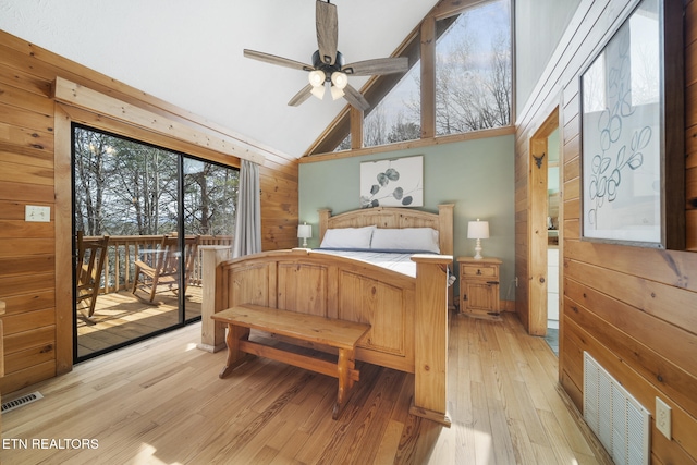 bedroom featuring visible vents, light wood finished floors, wooden walls, and access to exterior