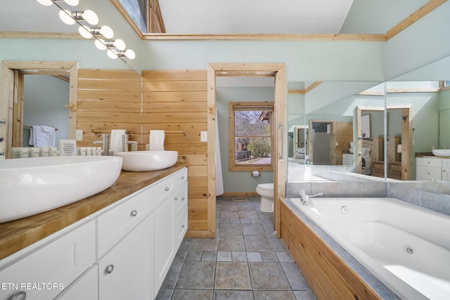 full bathroom featuring a tub with jets, double vanity, a sink, and toilet
