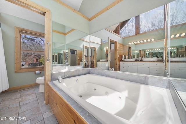 bathroom featuring toilet, baseboards, a healthy amount of sunlight, and a jetted tub