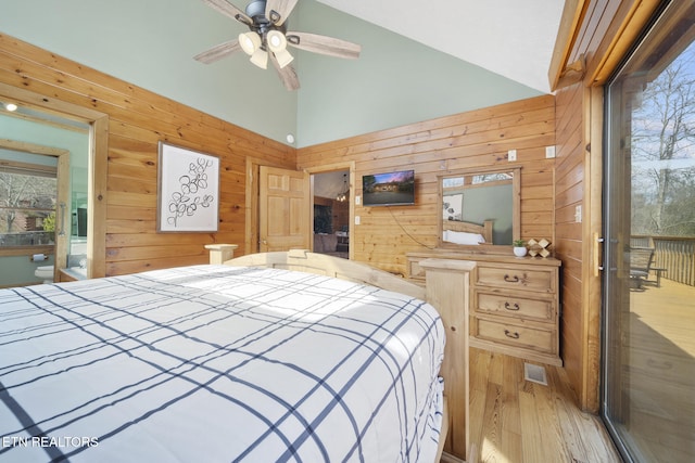 bedroom featuring high vaulted ceiling, wood walls, and wood finished floors