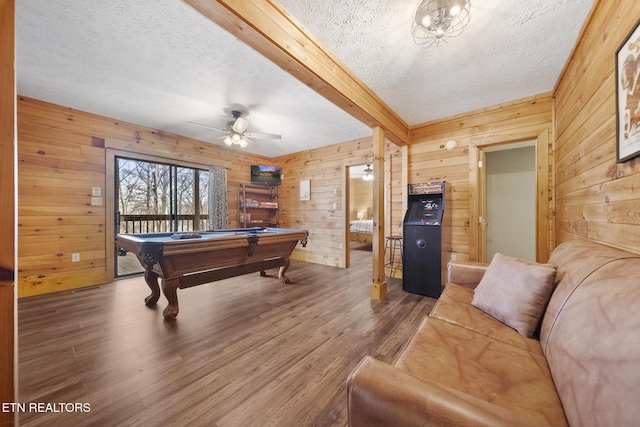 rec room featuring billiards, a ceiling fan, a textured ceiling, wood finished floors, and wooden walls