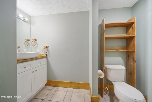 half bath with a textured ceiling, tile patterned floors, baseboards, vanity, and toilet