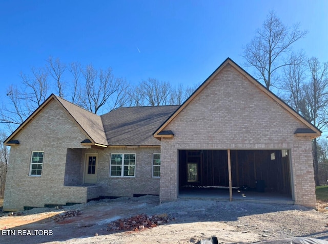 view of front of property featuring a garage, brick siding, and driveway