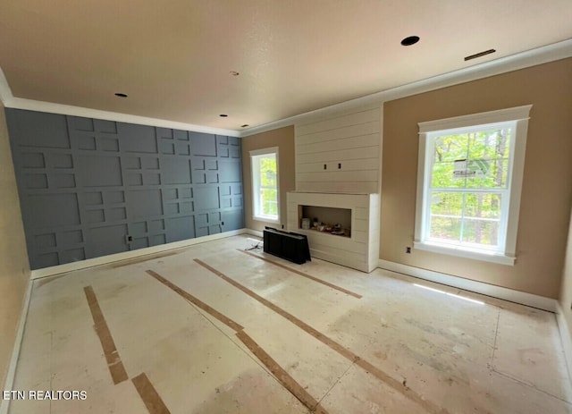 unfurnished living room featuring baseboards, ornamental molding, and a large fireplace
