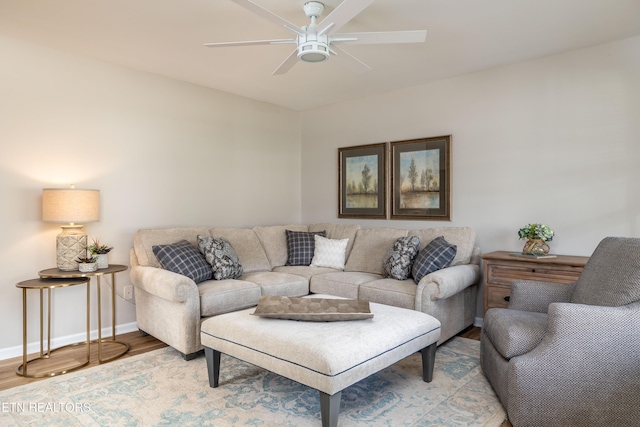 living area with a ceiling fan, baseboards, and light wood finished floors