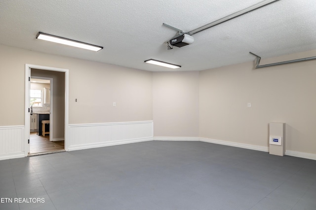 garage featuring a garage door opener and a wainscoted wall