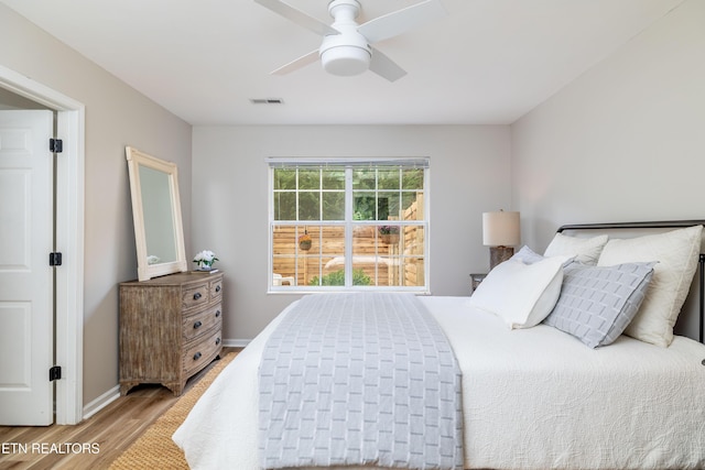 bedroom with baseboards, a ceiling fan, wood finished floors, and visible vents