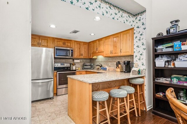 67 Eagle Ct, Crossville, TN 38558 - kitchen with light stone counters, decorative backsplash, appliances with stainless steel finishes, visible vents, and a peninsula