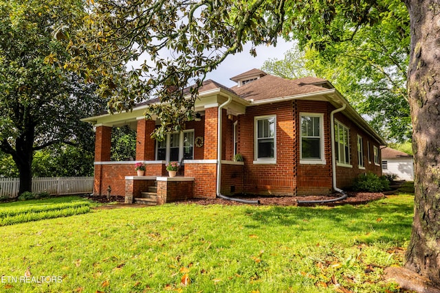 view of front of house with brick siding, fence, covered porch, and a front yard