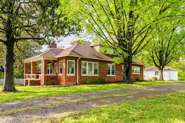 view of side of property with fence, a chimney, a lawn, and brick siding