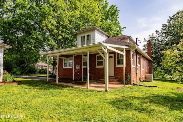 back of property featuring brick siding, central air condition unit, a yard, and a chimney
