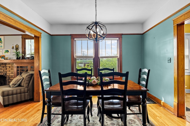 dining space featuring a fireplace, light wood finished floors, and a notable chandelier