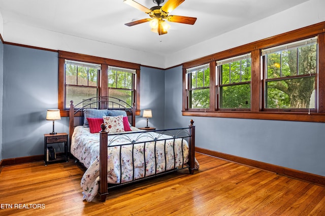 bedroom featuring a ceiling fan, baseboards, and wood finished floors