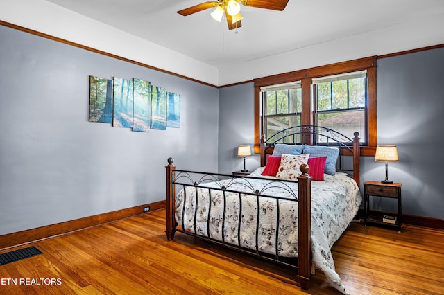 bedroom with baseboards, ceiling fan, wood finished floors, and visible vents