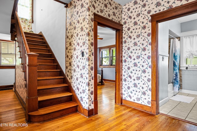 stairs featuring baseboards, wallpapered walls, and wood finished floors