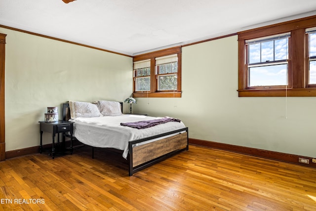 bedroom featuring wood-type flooring, baseboards, and ornamental molding