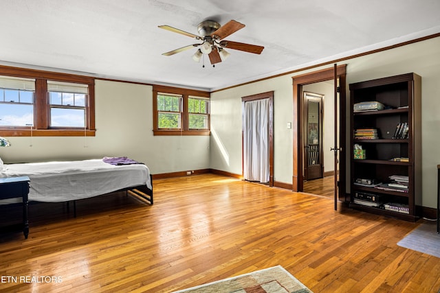 bedroom with baseboards, crown molding, hardwood / wood-style floors, and ceiling fan