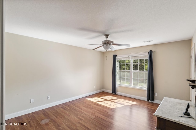 unfurnished living room featuring baseboards, a ceiling fan, wood finished floors, and visible vents