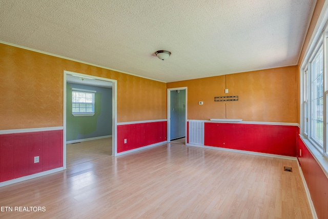 spare room featuring a textured ceiling, visible vents, wood finished floors, and baseboards