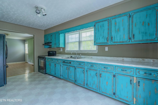 kitchen with freestanding refrigerator, light floors, under cabinet range hood, a sink, and black range with electric stovetop