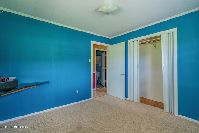 unfurnished bedroom with carpet, a closet, baseboards, and crown molding