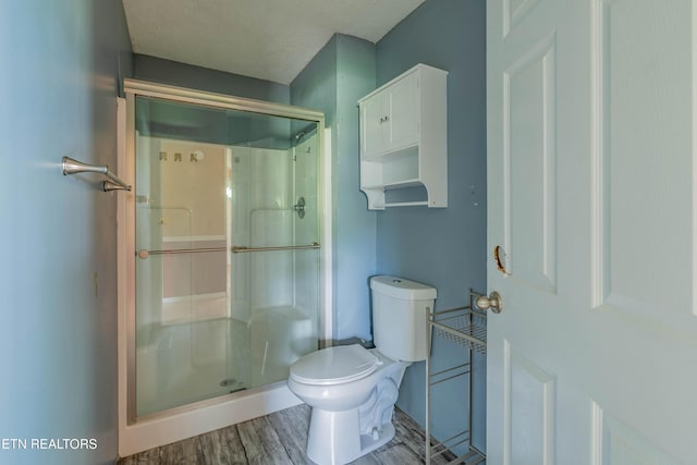 bathroom featuring a shower stall, toilet, and wood finished floors