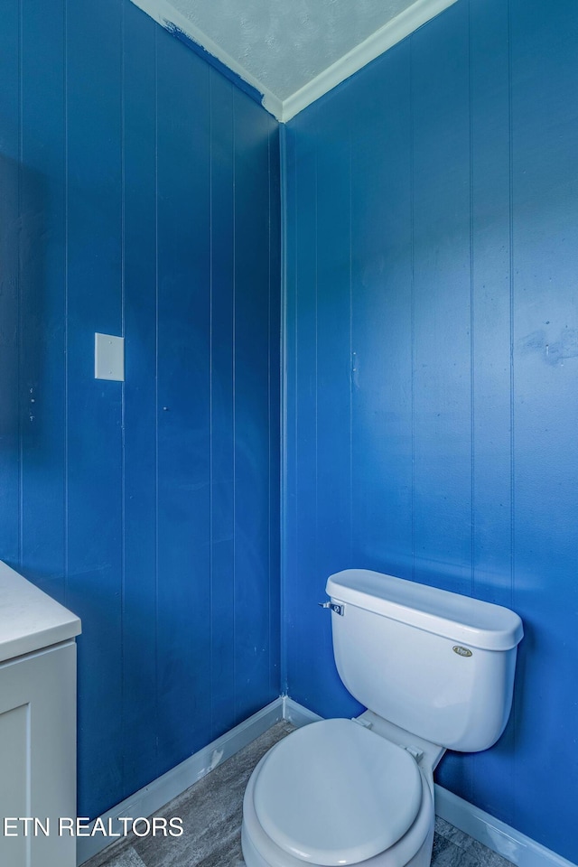 bathroom featuring crown molding, toilet, and baseboards