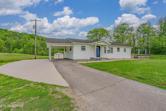 single story home with a front yard, an outdoor structure, aphalt driveway, and a carport